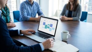 A leadership team meeting at a conference table, one leader reviewing a weekly calendar on a laptop while taking notes